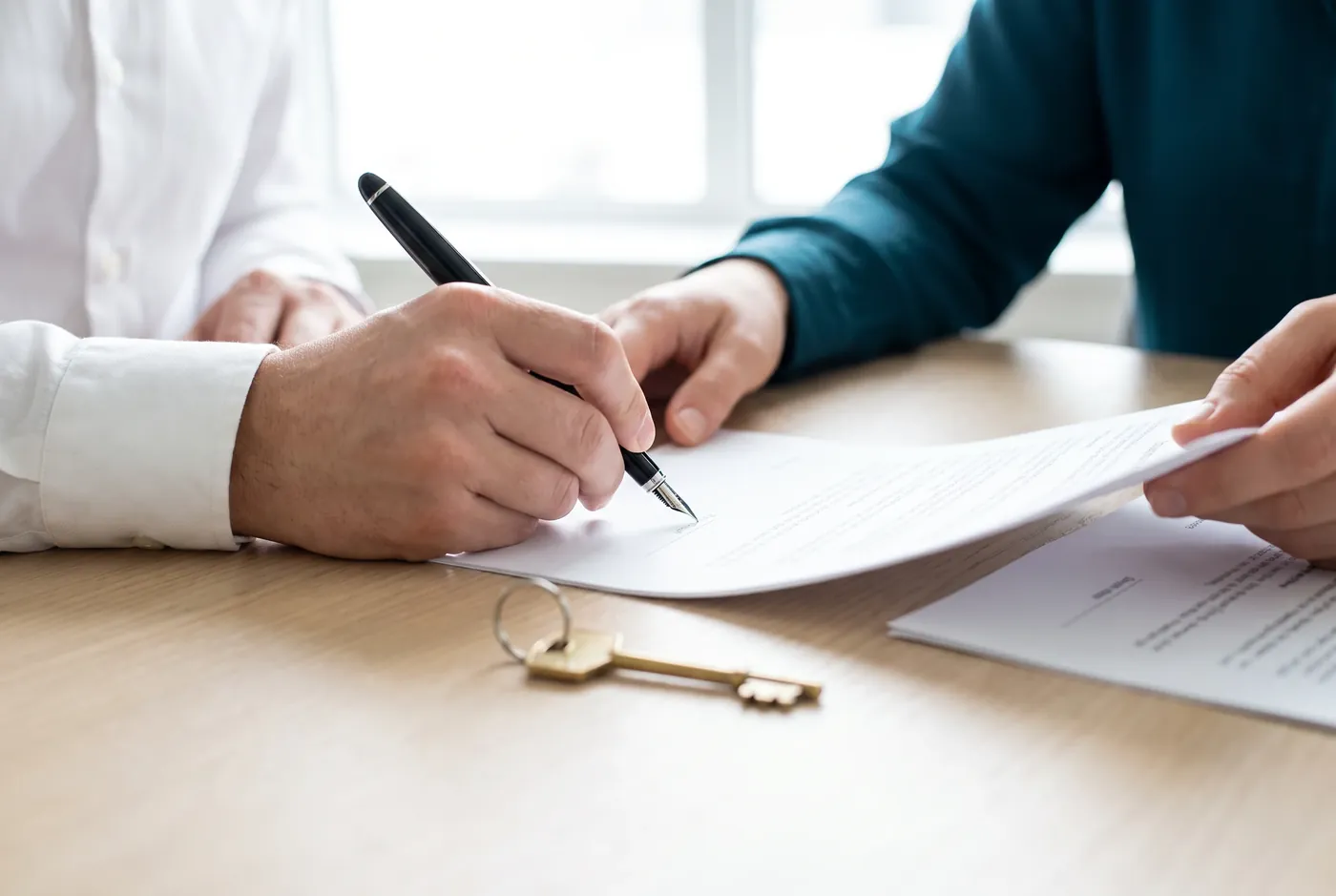 Firma de una escritura con pluma sobre la mesa
