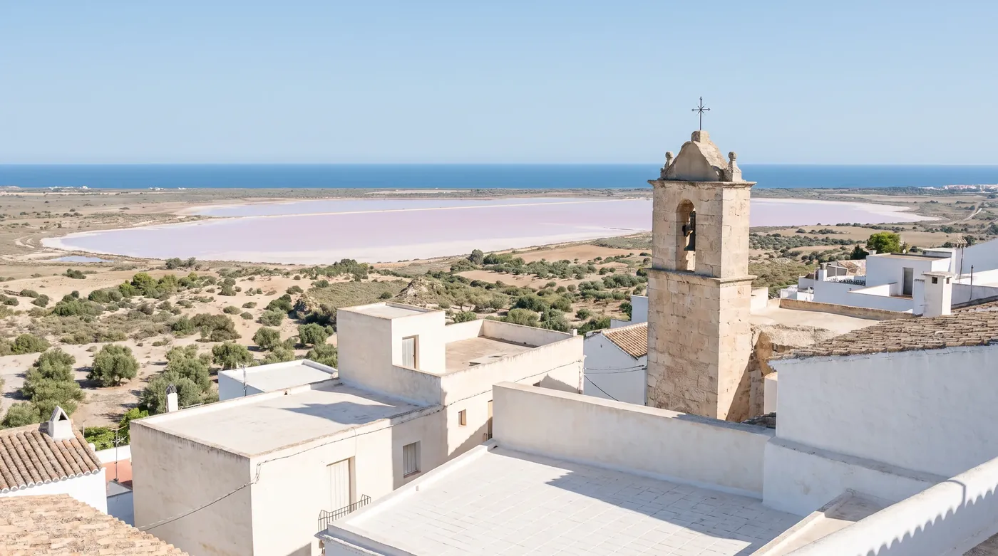 Pueblo encalado con su campanario y las salinas y el mar al fondo